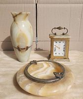 Front view of the set: agate ashtray with brass leaf rests, brass and agate clock, and solid agate vase showing natural veining.