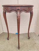 Front view of demi lune console table showing carved cabriole legs and curved apron with detailed leaf and shell carvings.