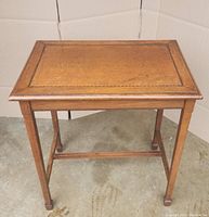 Full view of rectangular wooden side table showing the inlaid border on the tabletop and four solid legs with spade feet.