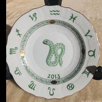 Full view of the Herend porcelain zodiac plate showing green snake motif and green zodiac symbols around edge with gold gild accents.