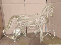 Side view of white painted steel wire frame horse with LED rope light outlining the shape standing on four legs.