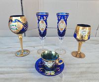 Front angle of the complete set showing all five pieces in cobalt blue Venetian glass with gold and floral decoration.