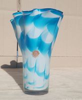 Front view of the ruffled blue and white glass vase with Nagoya sticker visible on body.
