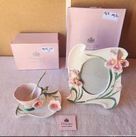 Photo showing the tea cup, saucer, spoon and the floral picture frame with boxes in background and Principe brand card