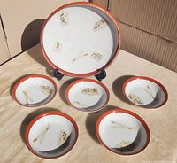 Set of six porcelain pieces including one large serving plate and five smaller plates, all decorated with Mahjong tile motifs and red rims.