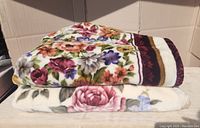 Two folded floral mink touch blankets stacked on top of each other showing patterns and colors