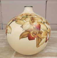 Front view of the round bulbous vase showing hand-painted magnolia flowers in beige, yellow, red and green on a cream glaze.
