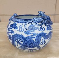 Front and side view showing detailed blue dragon motif and sculptured dragon emerging from rim on ceramic bowl.