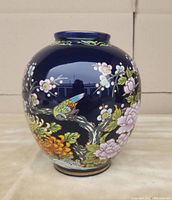 Front view of cobalt blue vase showing exotic bird on flowering cherry blossom branch with gold detailing.