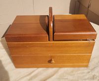 Wooden closed sewing box with two top compartments and drawer.