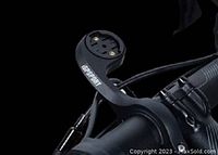 Close-up image of black iGPSPORT branded bike computer mount attached to bicycle handlebar, showing mounting arm and securing clamp with screws.