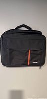 Front view of the Toshiba laptop carrying case showing exterior pocket with zip and a vertical red line design with Toshiba logo.