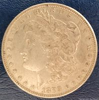 Obverse side of the 1879 Morgan silver dollar coin showing the profile of Lady Liberty, stars around the edge, and 'E PLURIBUS UNUM' inscription with date.
