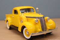 Yellow 1937 Studebaker Coupe Express Pick Up diecast metal model photographed outside box showing front and side details.