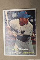 Front view of 1957 Topps Ernie Banks baseball card showing player in Cubs uniform and cap, holding bat.
