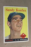 Front of 1958 Topps Sandy Koufax card showing head and shoulder image of Koufax in Dodgers cap on yellow background with name, team, and position text.