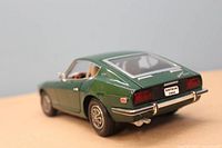 Rear three-quarter view of the green 1970 Datsun 240Z diecast model showing detail on bumper, lights, and rear window with visible interior.