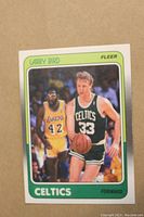 Close-up of Larry Bird 1988-89 Fleer basketball card showing player in Celtics green uniform dribbling ball with Lakers player in background.