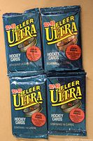 Four unopened 1992-93 Fleer Ultra Series I hockey card packs shown from the front in blue foil packaging with yellow Fleer Ultra logo, each containing 14 cards.
