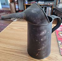 Side view of antique metal oil can showing integral funnel and '1 Qt. Liq'd' marking.