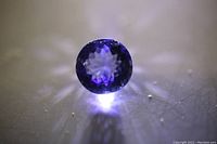 Blue tanzanite gemstone illuminated from below to show color and facets.