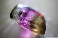 Close-up view of the watermelon tourmaline showing its unique cut and internal inclusions with vibrant green, pink, and yellow coloration.