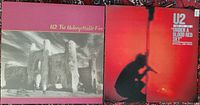 Front covers of the two U2 vinyl albums side by side. 'The Unforgettable Fire' with monochrome castle image on red background, and 'Under a Blood Red Sky' with red silhouette stage image.