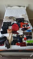 Full view of all bags, purses, wallets, gloves, and eyeglasses across bed.