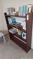 Full view of dark brown wooden bookshelf with multiple shelves holding books.