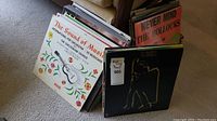 Photo showing multiple vinyl records arranged leaning against a couch, featuring 'The Sound of Music' album and 'Never Mind the Bollocks' album prominently visible.