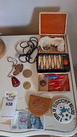 Lot contents laid out on a white table including miniature bowling sets in boxes, coins, leather pouch, soccer bug button, and copper jewelry pieces.