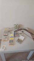 White table with assorted collectible educational cards laid out, two coin rolls, and wooden coat hanger