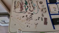 Overhead photo showing full assortment of costume jewelry items laid out on a table including necklaces, bracelets, rings, earrings, and pins.
