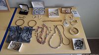 Overview of gold and costume jewelry laid out on yellow table