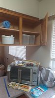 Oster convection oven with kitchen accessories on countertop beneath kitchen cabinets