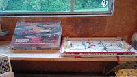 Photo showing Super Fast electric race track box and All-Star hockey game side by side on table.