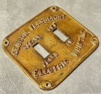 Front view of bronze vintage switch face plate with embossed lettering and switch cutouts.