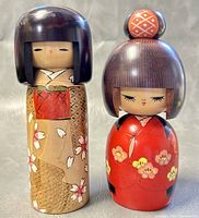 Front view of two 8-inch Kokeshi dolls, showing painted kimono designs and hairstyles