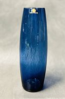 Front angle view of the 7-inch dark blue Finnish Iittala glass vase showing its tall narrow form and original brand tag.