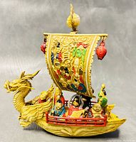 Full view of the yellow celluloid dragon sailboat with colorful Seven Lucky Gods figurines and red lanterns.