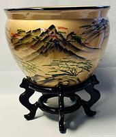 Front view of the ceramic planter pot on the wooden base showing the hand-painted Chinese landscape design.