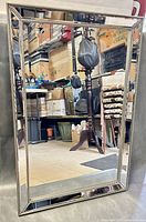 Full view of the large rectangular beveled wall mirror showing studded decorative frame and clear reflective surface.