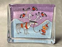 Rectangular glass paperweight showing front face artwork with reindeer, elf, birds and snowy background under purple sky.