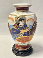 Photo of front side of Japanese hand painted vase showing detailed traditional figure with blue clothing and gold accents.