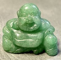 Front view of the miniature jade carved laughing Buddha figurine showing facial features and seated position