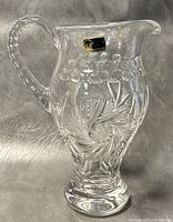 Side view of crystal pitcher showing clear ornate pinwheel and leaf cut designs and original Lausitzer label.