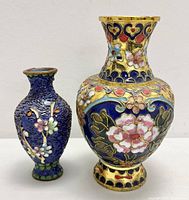 Pair of antique Chinese cloisonné vases, one small navy blue and one larger multicolored with floral patterns.