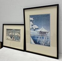 Both framed prints displayed side by side on table against white wall