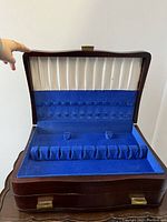 Open top lid showing white pleated fabric and blue velvet cutlery straps inside the lid and base compartments for cutlery storage.