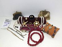 Wide view of the lot showing all jewelry pieces, watches, and mesh purses on display with a red stand for some items